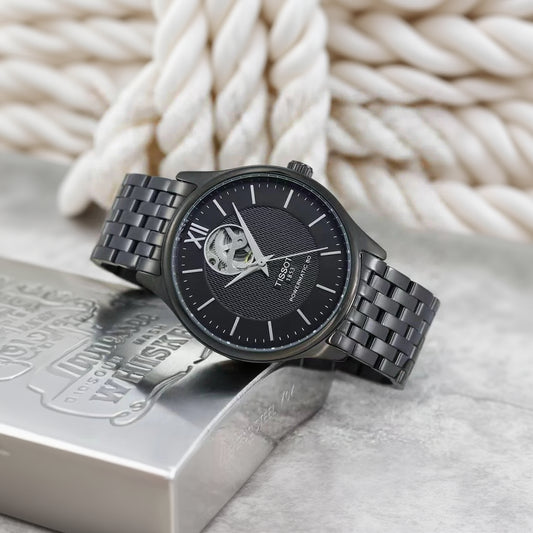 Black Tissot watch with metal strap on a textured surface